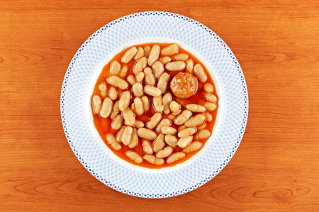 Baked beans and chorizo in tomato sauce on wood background. Shallow depth of field