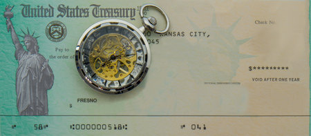 Photo of blank US Treasury check mock up with a modern pocket watch on top. Treasury check has statue of liberty imageの写真素材