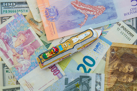 A miniature cruise ship on a background of international currencies, top down viewの写真素材