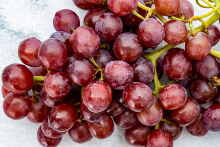 A close up of a bunch of juicy red grapes with stems on a white marble countertop, clean modern lookの写真素材