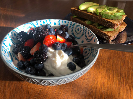 Avocado toast and bowl of berries and yogart breakfast