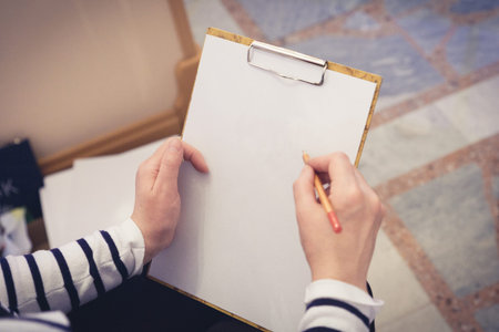 An artist holding a paper clipped on a file and a pencil for drawingの写真素材