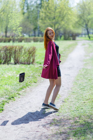 A young girl with red hair walks in the Park in a good mood. Happy girl.の写真素材