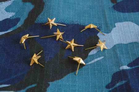 Gold stars for shoulder straps on blue camouflage fabric. Military emblems of Russian troops and services. No people. Photoの写真素材