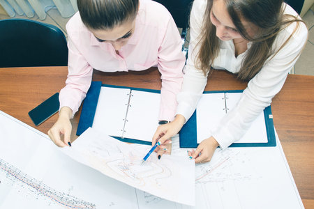 Discussion of the project in the office. Architects with drawings in the office planning work. Girls...