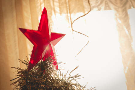 Decorated Christmas tree. Big red star on top of Christmas tree. Soft focus on the sunlight fromの写真素材