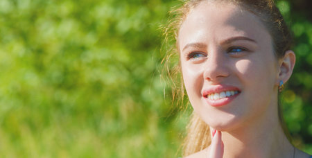 Happy beautiful girl in the sun smiling looking at the sun. A cheerful young girl smiles and touches...