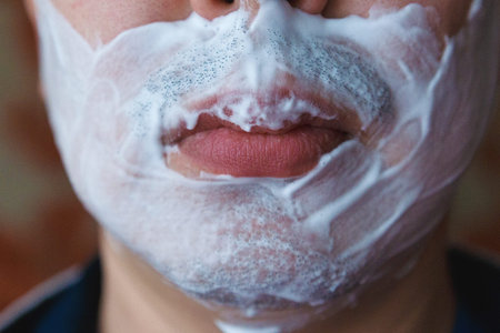 Close-up of male lips and stubble. Stubble on the face around the lips in shaving foam.