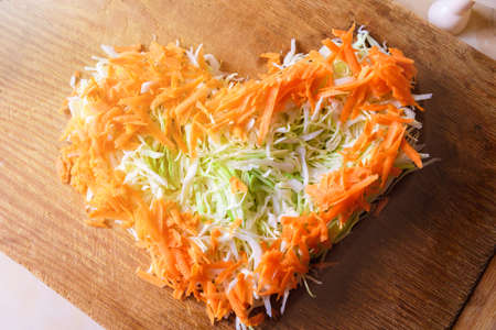 White cabbage and carrots finely chopped in the shape of a heart. Concept of love for vegetarian cuisine and raw vegetables.の写真素材