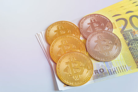 Golden bitcoin coins on the background of 200 Euro paper notes. The concept of trading and the value...
