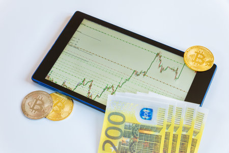 Growing chart on the currency exchange on the smartphone screen with bitcoin and paper currency Euro...