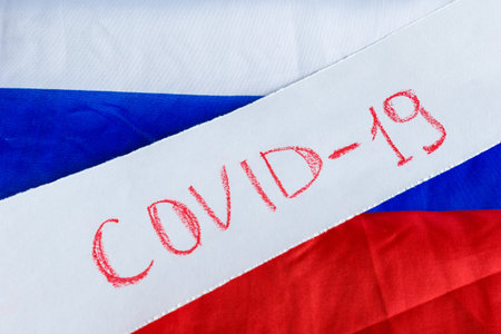 The name of the Covid-19 coronavirus on the background of the flag of the Russian Federation.