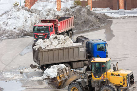 Novokuznetsk. Russia. 09.04.2020. Cleaning the territory from snow with heavy equipment and loading into trucks. Editorial.のeditorial素材