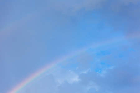 A piece of rainbow in the sky against the background of rain cloudsの写真素材