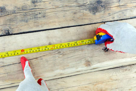 A male hand in work gloves points with the index finger to the length of the measuring tape. Side view.の写真素材