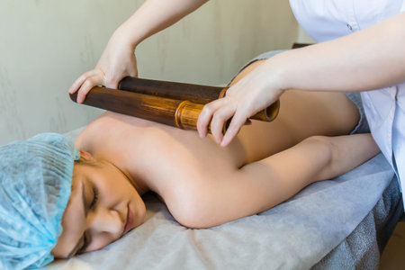 Body massage with bamboo sticks. Oriental method of back massage with bambooの写真素材