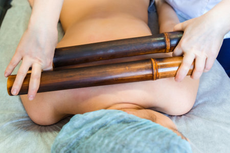 Body massage with bamboo sticks. Oriental method of back massage with bambooの写真素材