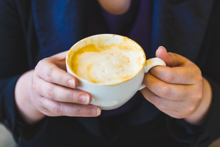 A cup of coffee cuppuccino in female hands.の写真素材