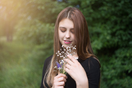 Young woman with a small bouquet of wildflowers.の写真素材