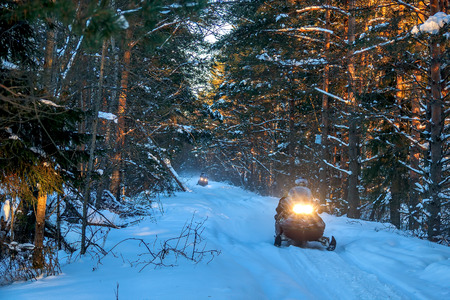 Snowmobiles travel on a winter forest road far from civilization.の写真素材
