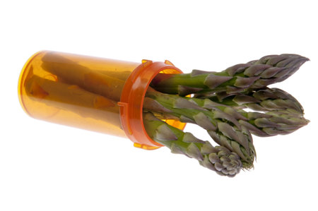 Asparagus sprouts out of an orange prescription bottle as a symbol of good health.  Medicine can make you healthy but eating fresh vegetables is another way to good health.  Great image for health care related issues.の写真素材