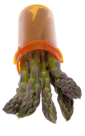 Asparagus sprouts out of an orange prescription bottle as a symbol of good health.  Medicine can make you healthy but eating fresh vegetables is another way to good health.  Great image for health care related issues.の写真素材