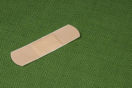 A single plaster on a green background, studio lighting.の写真素材