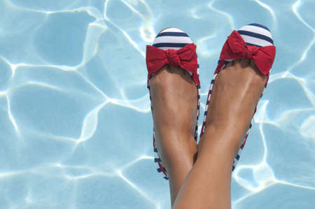 A woman sports some nautical shoes with a pool on a sunny day as the background.  A great shot for summer or 4th of July because of the red, white and blue coloring of the photograph.の写真素材