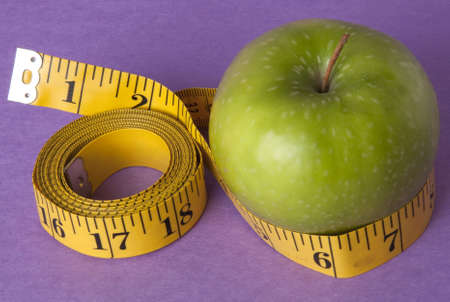 Granny Smith Green Apple with a bright yellow tape measure represents the concepts of diet and healthy lifestyle. Perhaps this is your New Year's Resolution?の写真素材