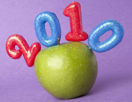 2010 Health and Education is represented with the numbers 2010 and a bright green apple on a vibrant purple background.の写真素材