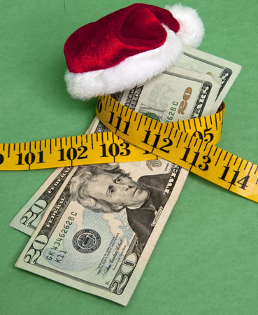 Money squeezed by a measuring tape representing a tight holiday budget.の写真素材