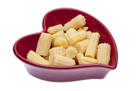 Baby corn in a heart shaped dish isoalted on white with a clipping path.の写真素材