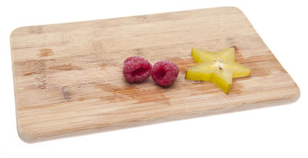 Fresh Raspberries and Carambola Starfruit on a Cutting Board. Isolated on white with a clipping...