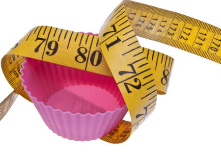Diet themed image with vibrant pink cupcake tin and measuring tape.  Isolated on white with a clipping path.の写真素材