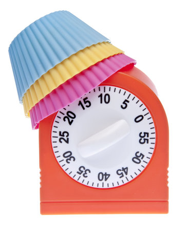 Cupcake wrappers and a kitchen timer create a baking themed image isolated on white with a clipping...