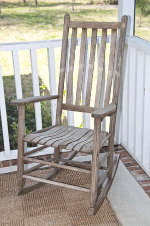 Worn wooden rocking chair on a screened in porch.の写真素材