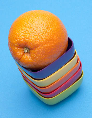 Bright fresh orange in a pile of vibrant orange bowls on a bright blue background.の写真素材