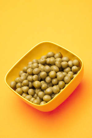 Vibrant bowl of canned peas on a yellow background.の写真素材