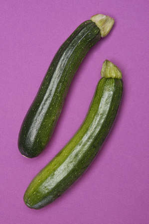 Pair of fresh zucchini on a vibrant purple background.の写真素材