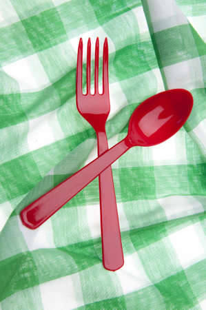 Red Plastic Fork and Spoon on a Green Picnic Blanket.の写真素材