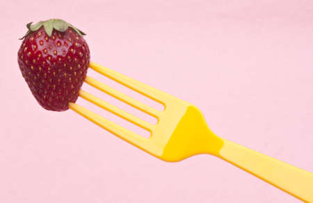 Fresh Summer Strawberry on a Vibrant Yellow Fork.の写真素材
