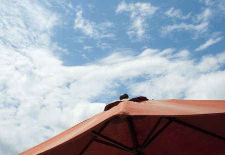 Relaxing Blue Sky with Clouds as Seen from Under a Vibrant Red Umbrella.の写真素材