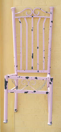 Retro Worn Pink Chair on a Yellow Wall.の写真素材