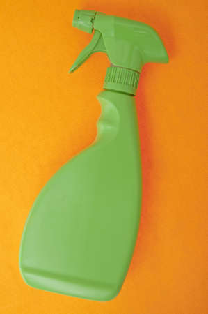 Green Cleaning Spray Bottle on Vibrant Modern Orange Background.の写真素材