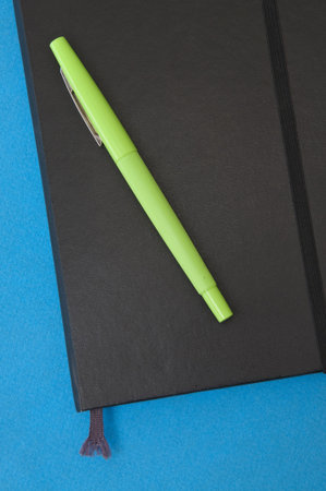Vibrant Green Pen and Notebook on a Blue Background.