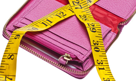 Tight Budget Concept with Open Wallet Squeezed by a Measuring Tape.