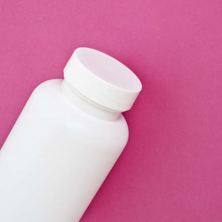 White Bottle of Vitamins on Vibrant Pink Background.の写真素材