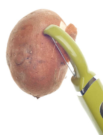 Sweet Potato Being Peeled with Green Vegetable Peeler.の写真素材