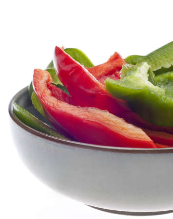 Fresh Cut Green and Red Bell Peppers Close Up in a Bowl Isolated on White.の写真素材