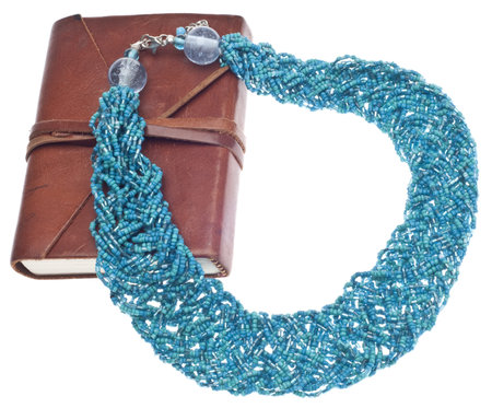 Fashion Blogging Concept with Teal Necklace and Brown Journal on White.の写真素材
